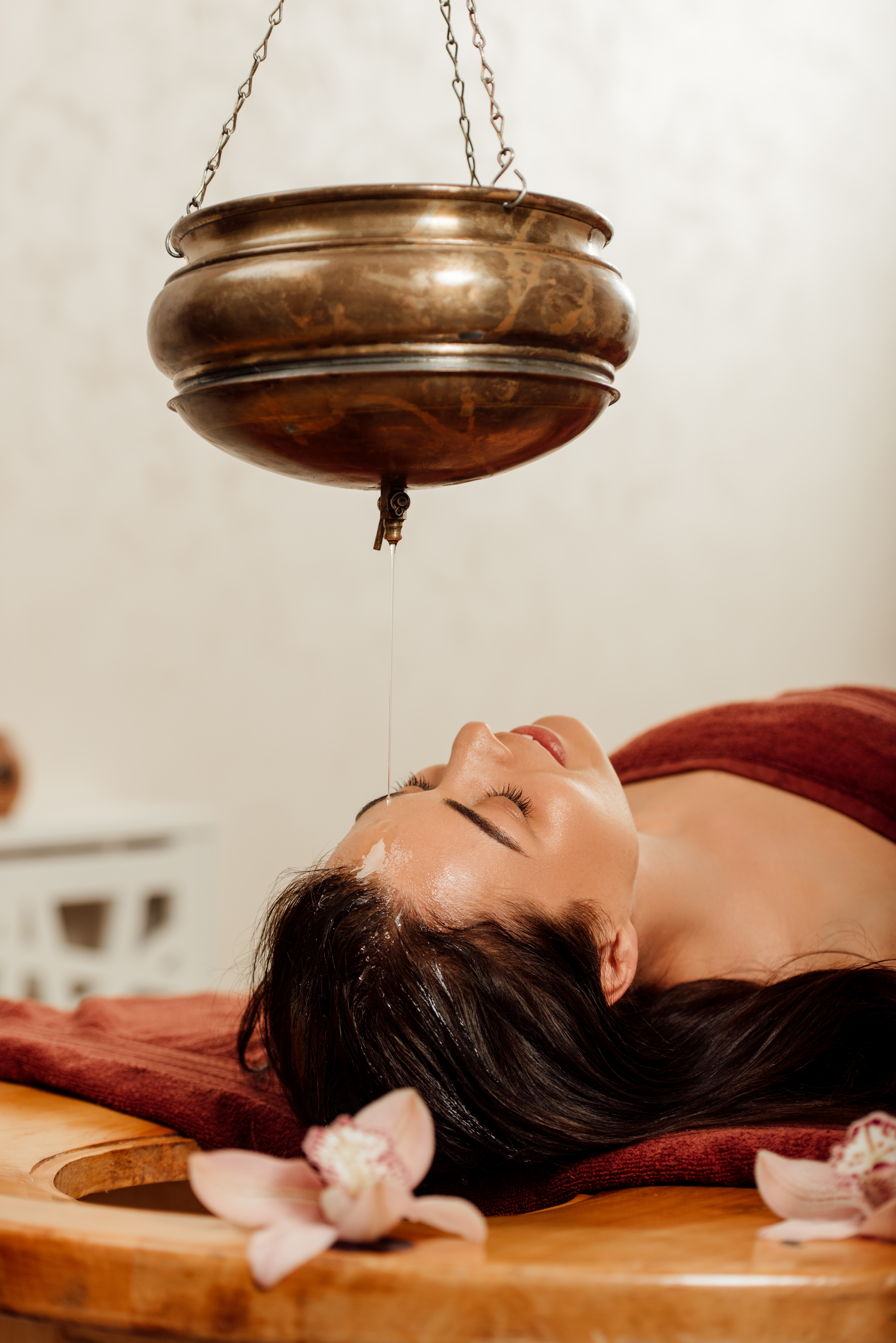 Relaxed Young Woman Lying Under Shirodhara Vessel